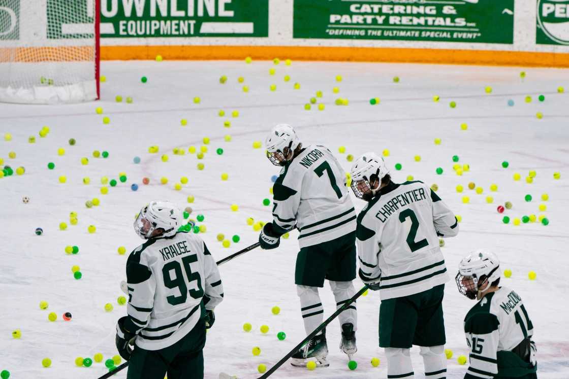 Big Green hockey players on the ice with tennis balls