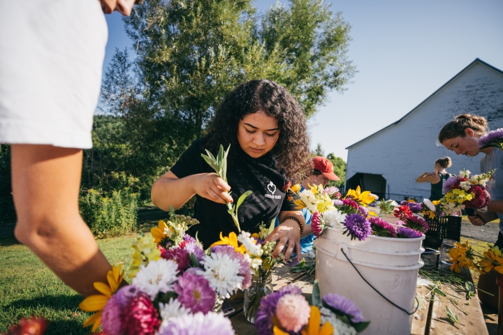 Student arranging flowers in buckets at the Organic Farm