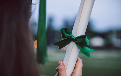 student holding a rolled-up diploma