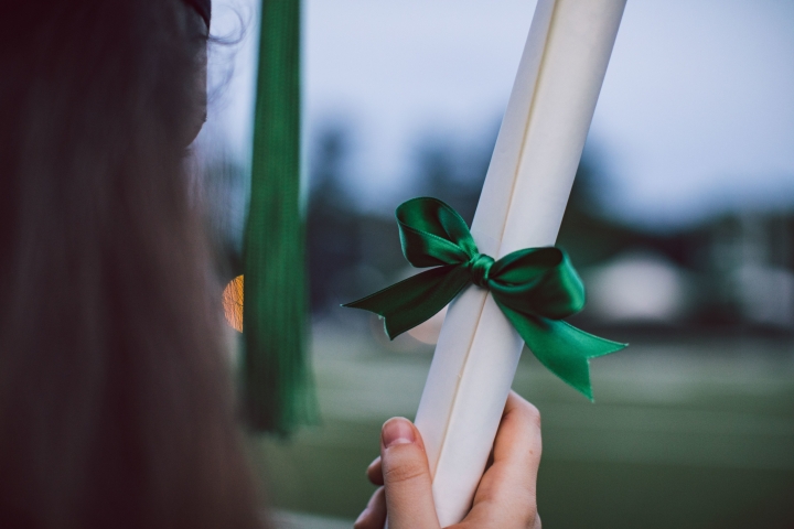 student holding a rolled-up diploma