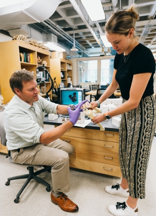 Two people holding orthopedics lab tools