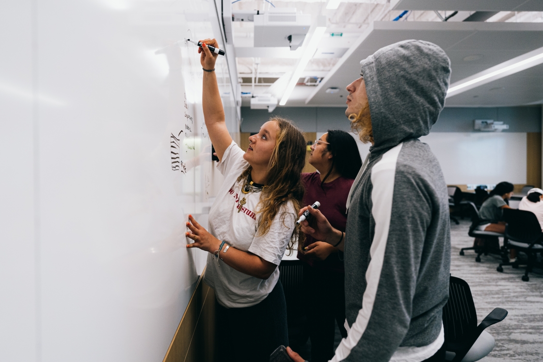 Students writing on a whiteboard