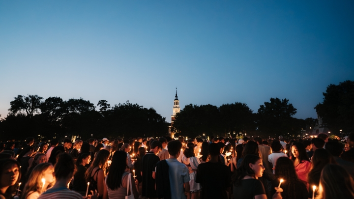 Students holding candles on the Green and dusk