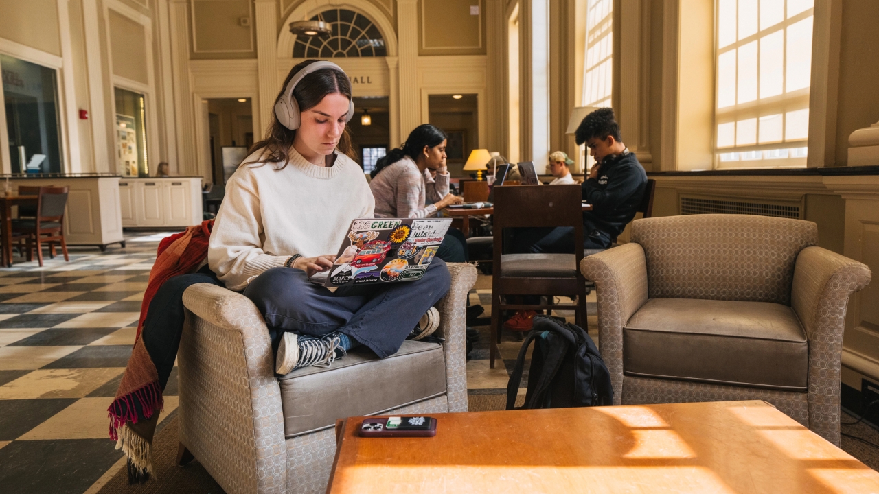 A student with a laptop in Baker Library