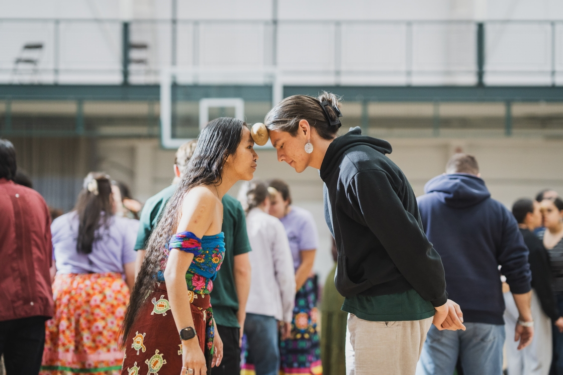 Two people hold a potato between their foreheads