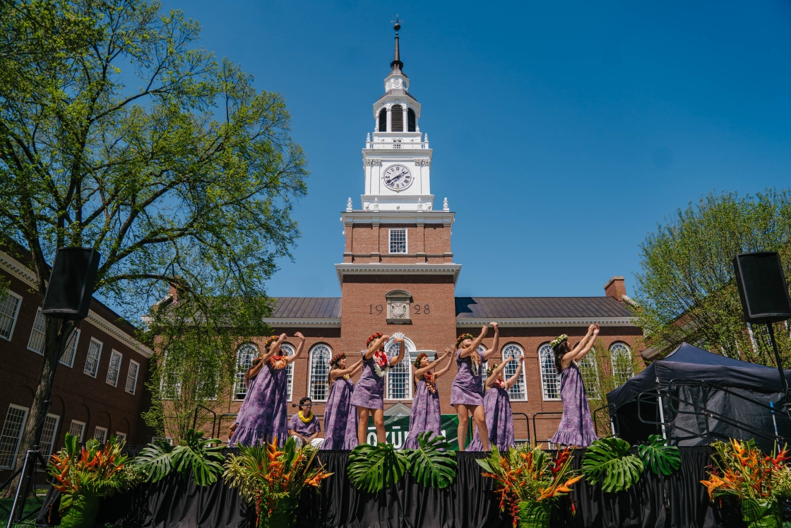 Students dance on stage in front of Baker Tower