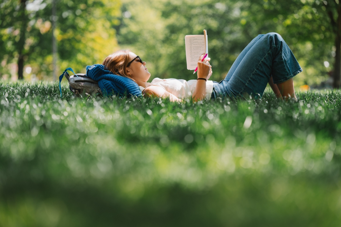 Eliza Dunn lying in the grass reading