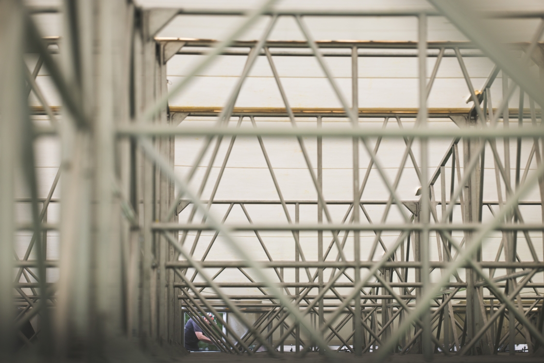 Crew member working, seen through sets of truss
