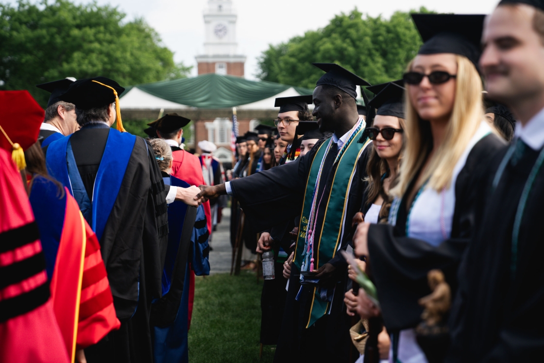 A professor and student shake hands during the academic procession