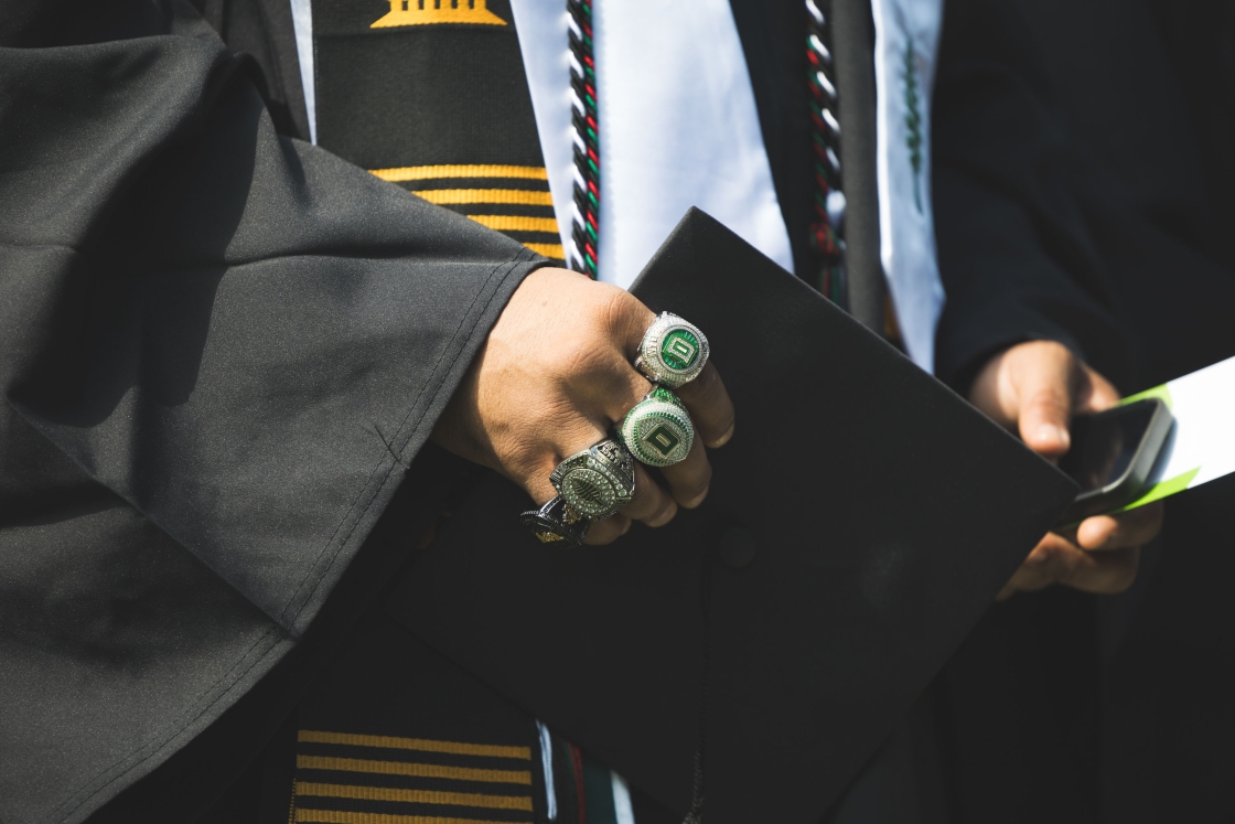 A football players hand, adorned with 4 large championship rings