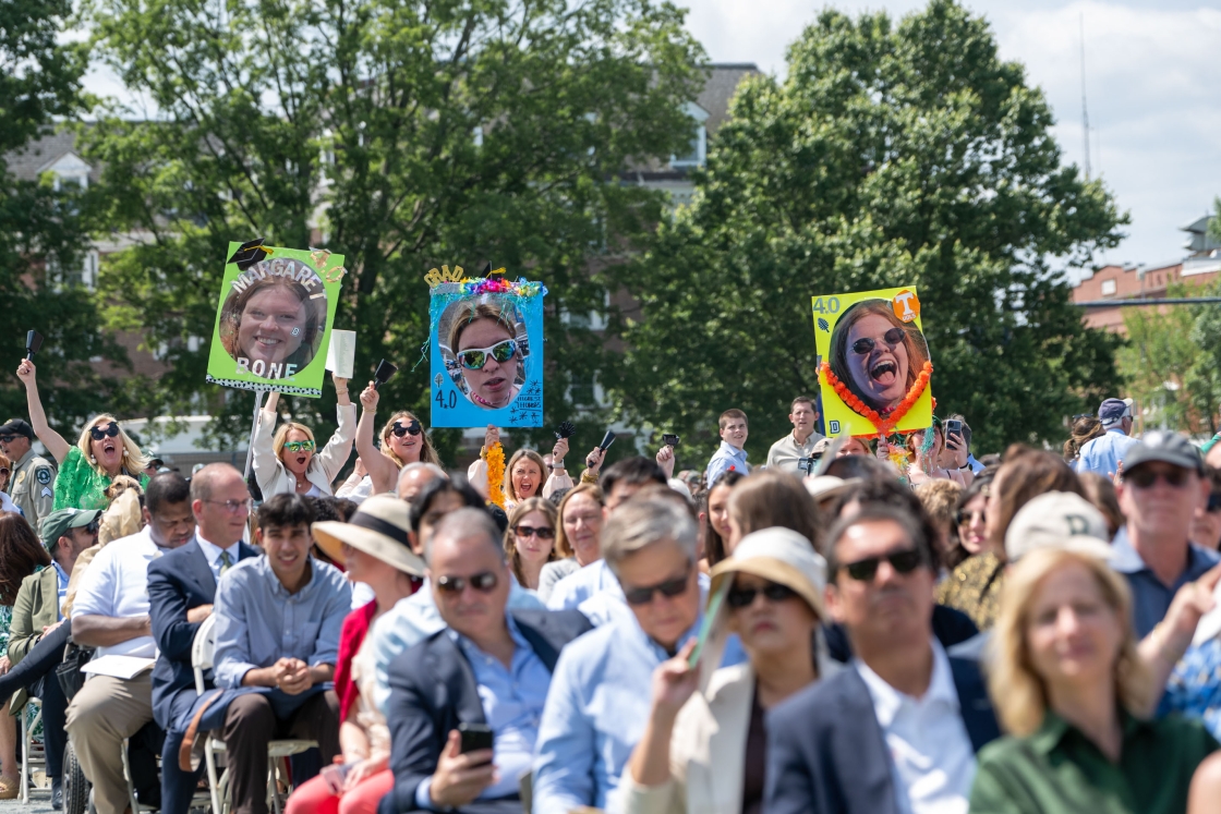 A family holds up 3 comedic signs for their graduate