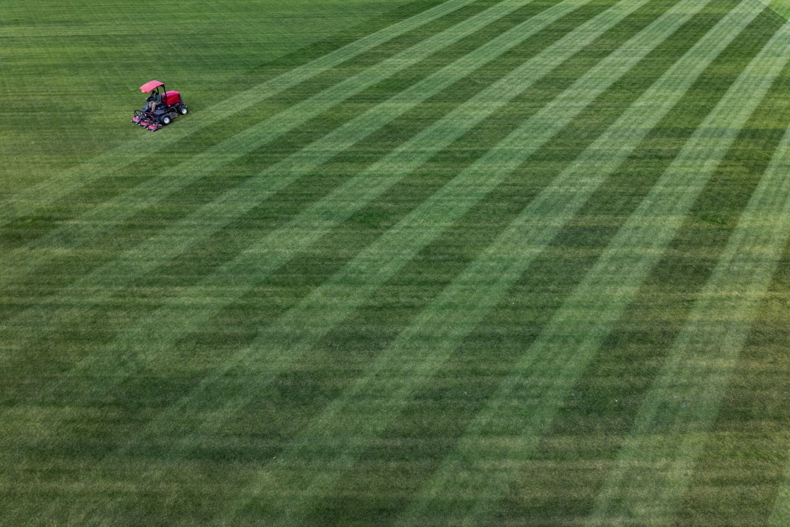Aerial of a mower creating a pattern in the grass