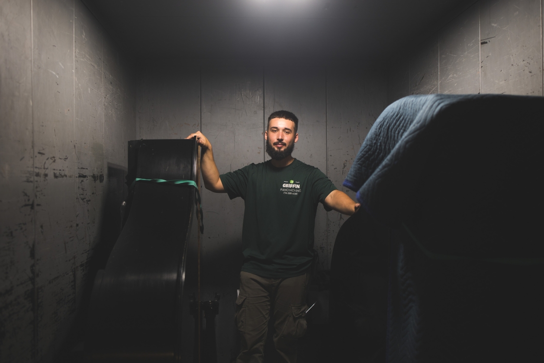 Grayson Keane riding an elevator with pianos