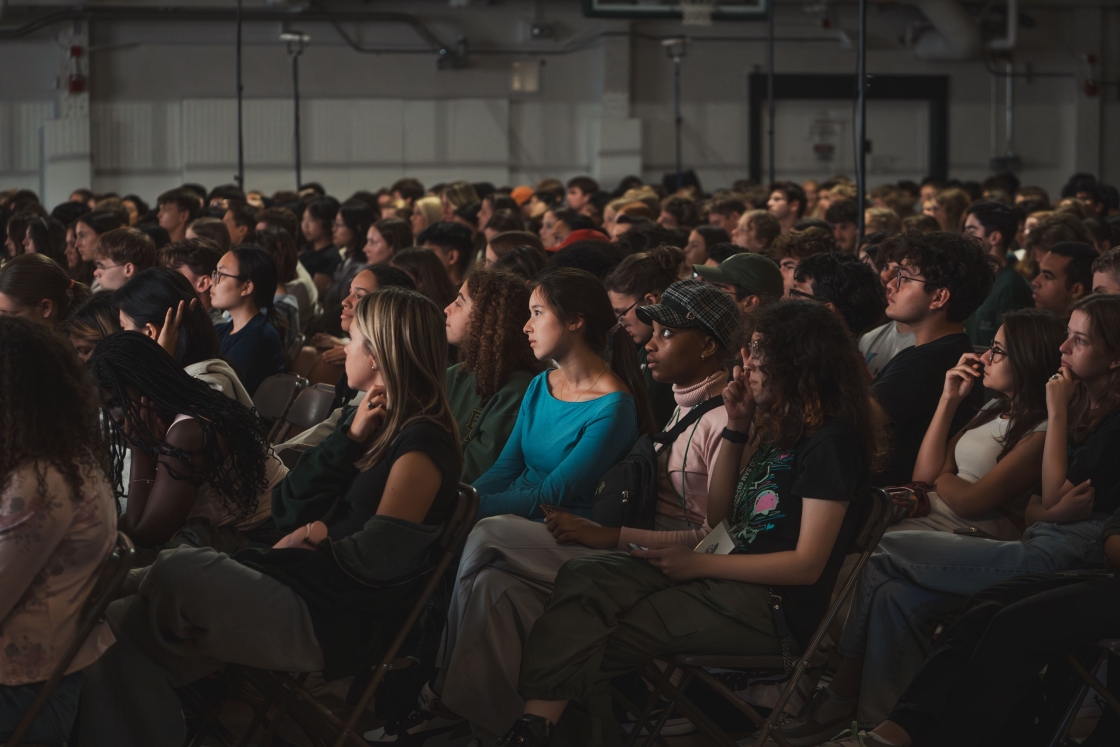 Students sit in a dim auditorium