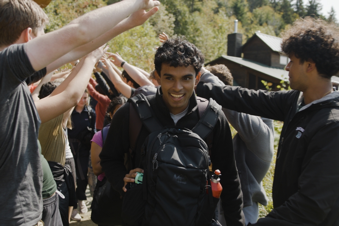 Student with backpacks walking under arm bridges