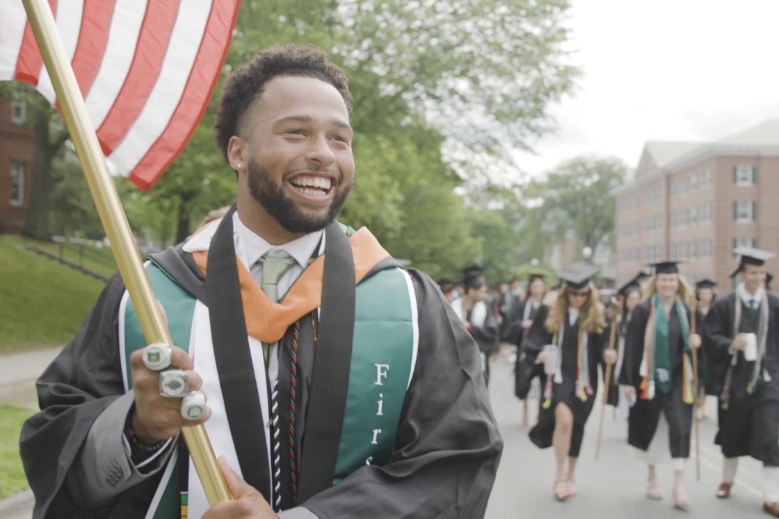 Student holding American flag in grad regalia