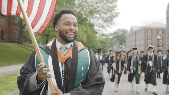 Student holding American flag in grad regalia