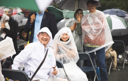Parents at Dartmouth Commencement stand in the rain with umbrellas