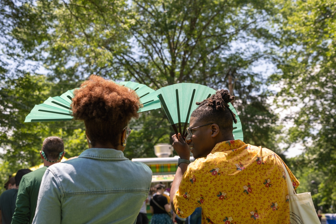 People holding paper fans up to shield the sun
