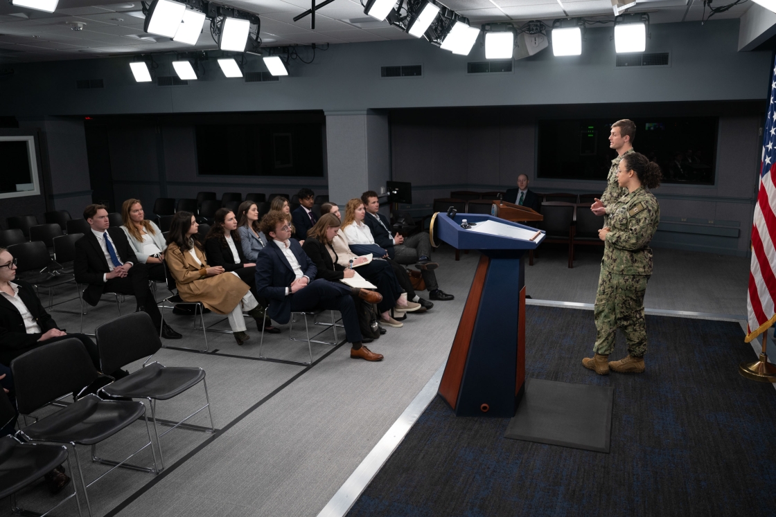 Two people in uniform talk to an audience