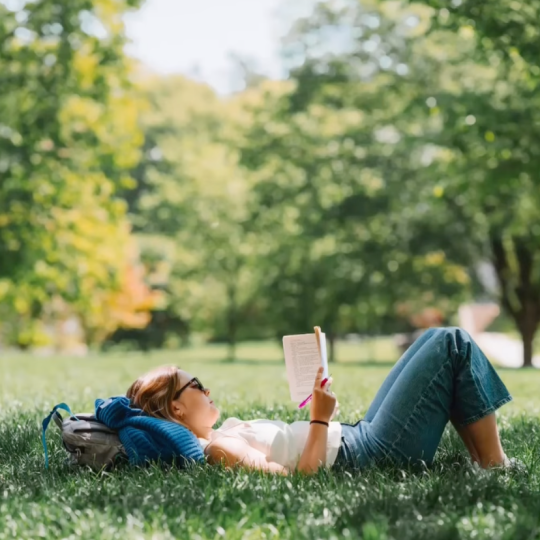 Woman lying in grass reading a book